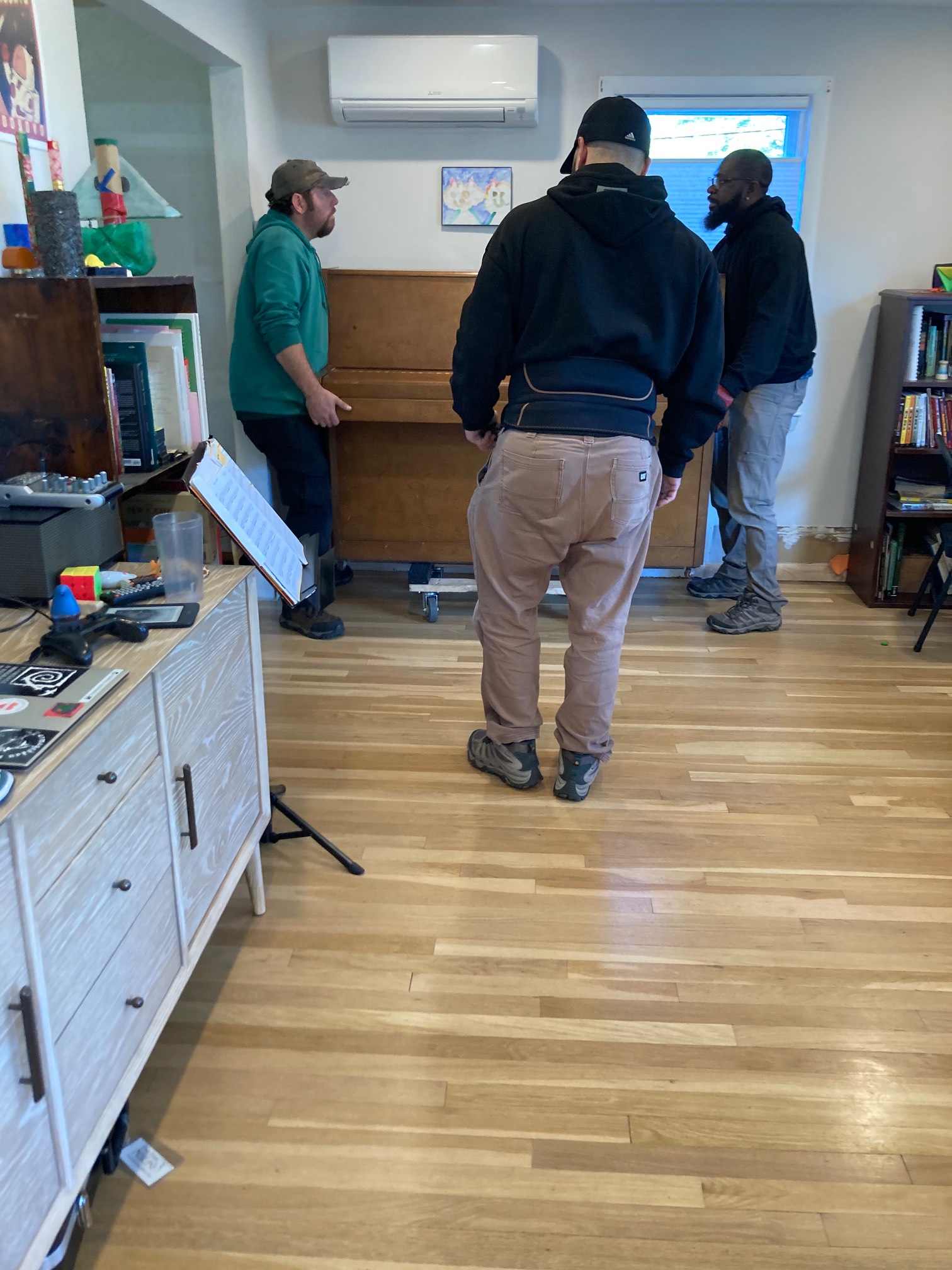 Three movers lifting piano