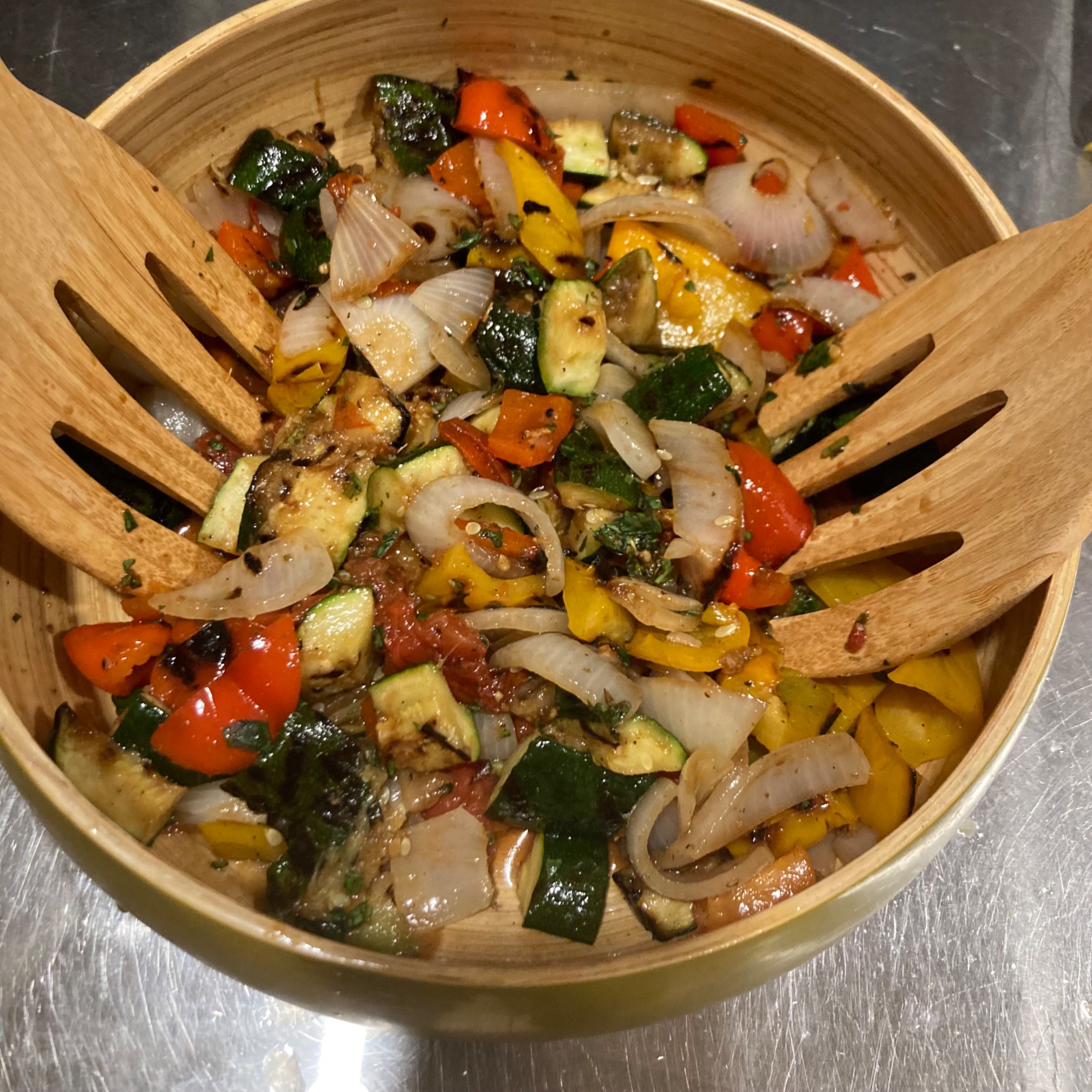 Grilled vegetables and salad hands in a wooden bowl