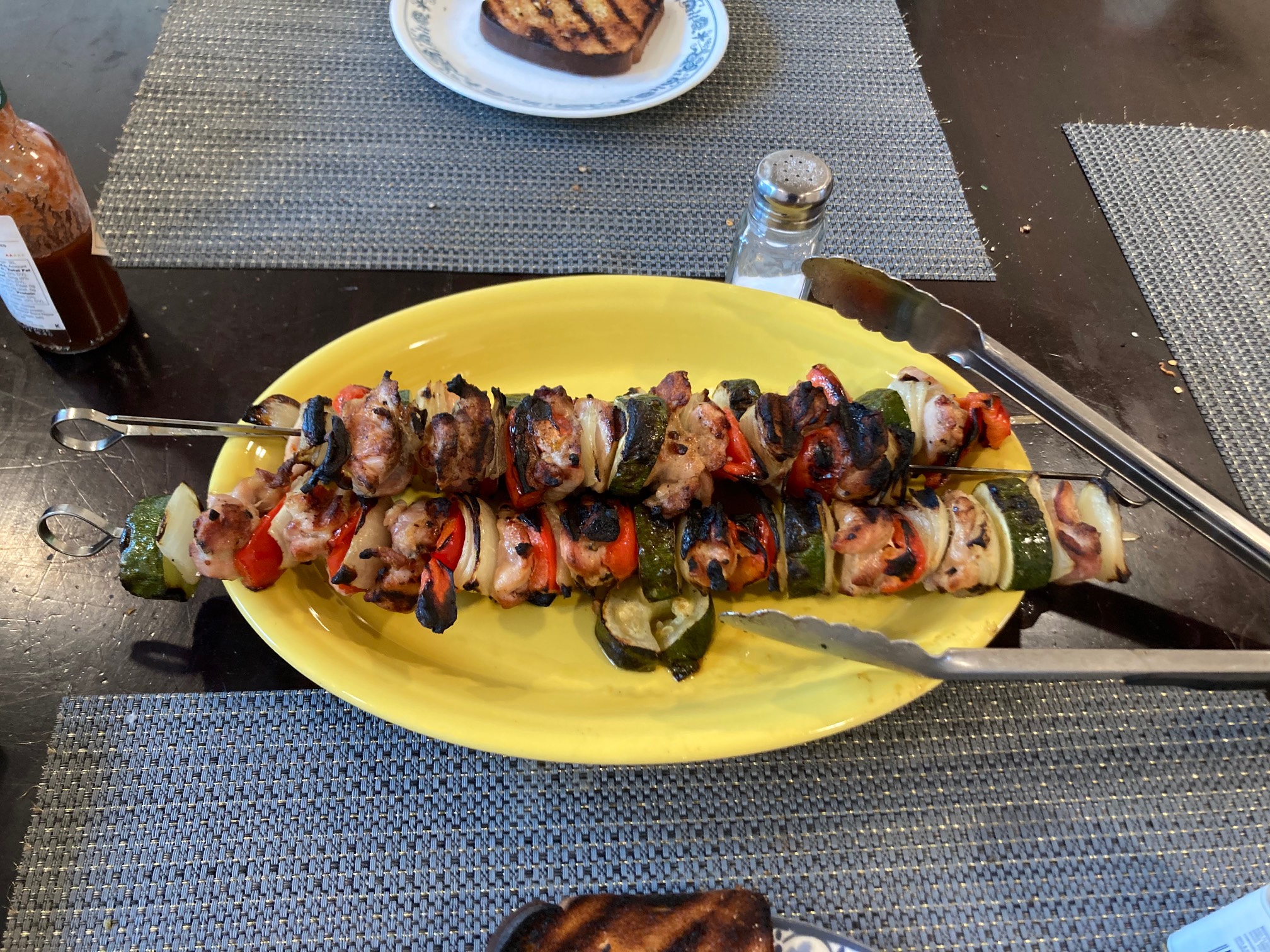 Two skewers with chicken, onion, peppers, and zucchini on a plate