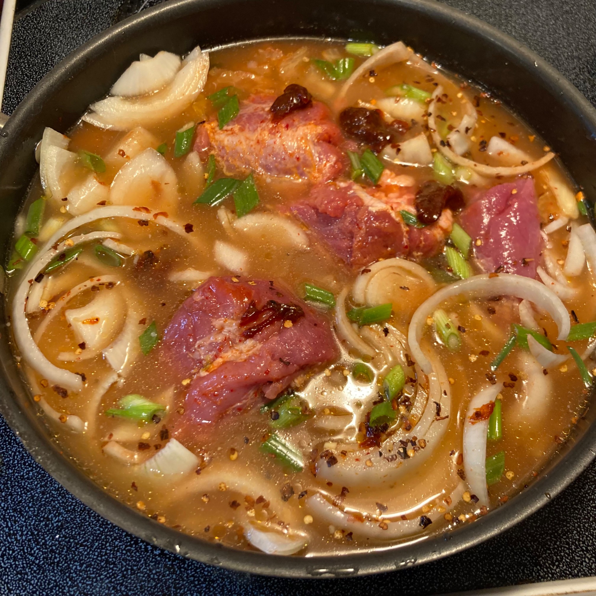 Deep pan with kimchi, pork, onions, and broth