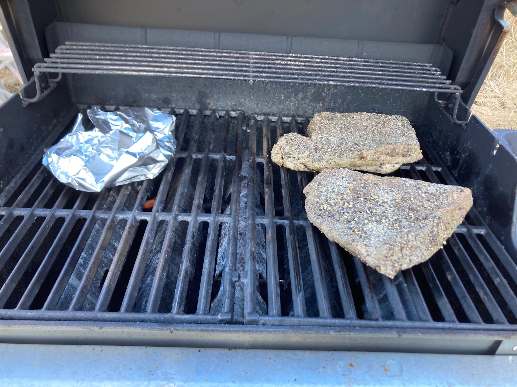 Grill with foil packet and two piece of beef on it