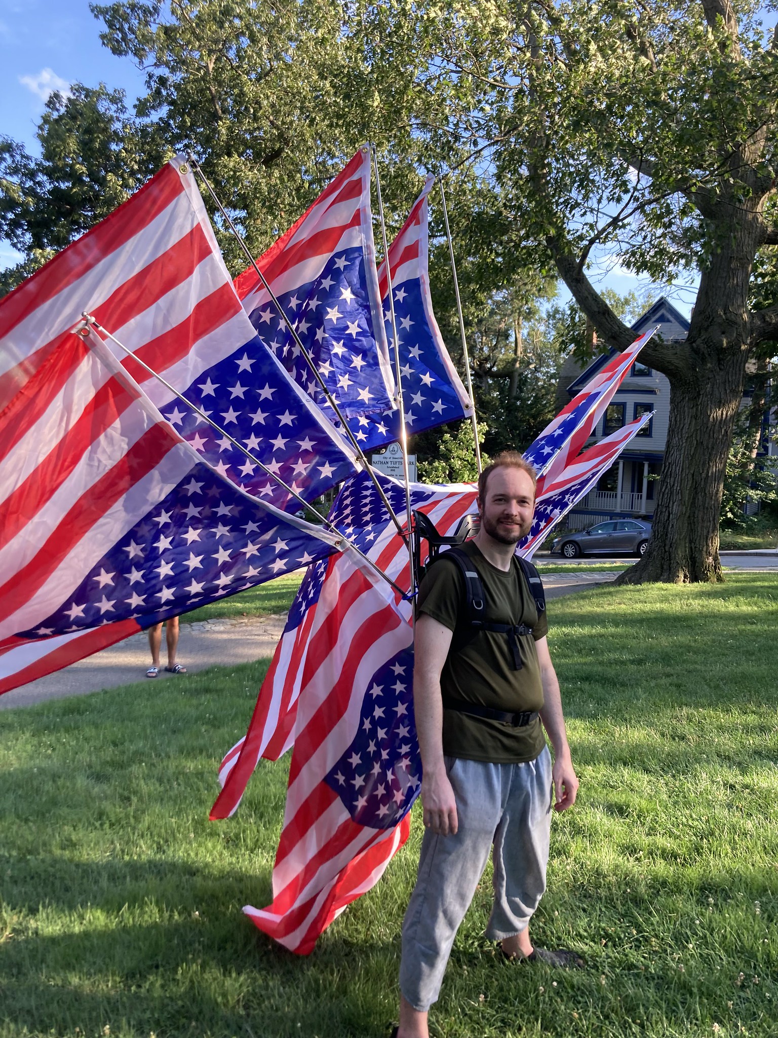 Man with about eight US flags on his back