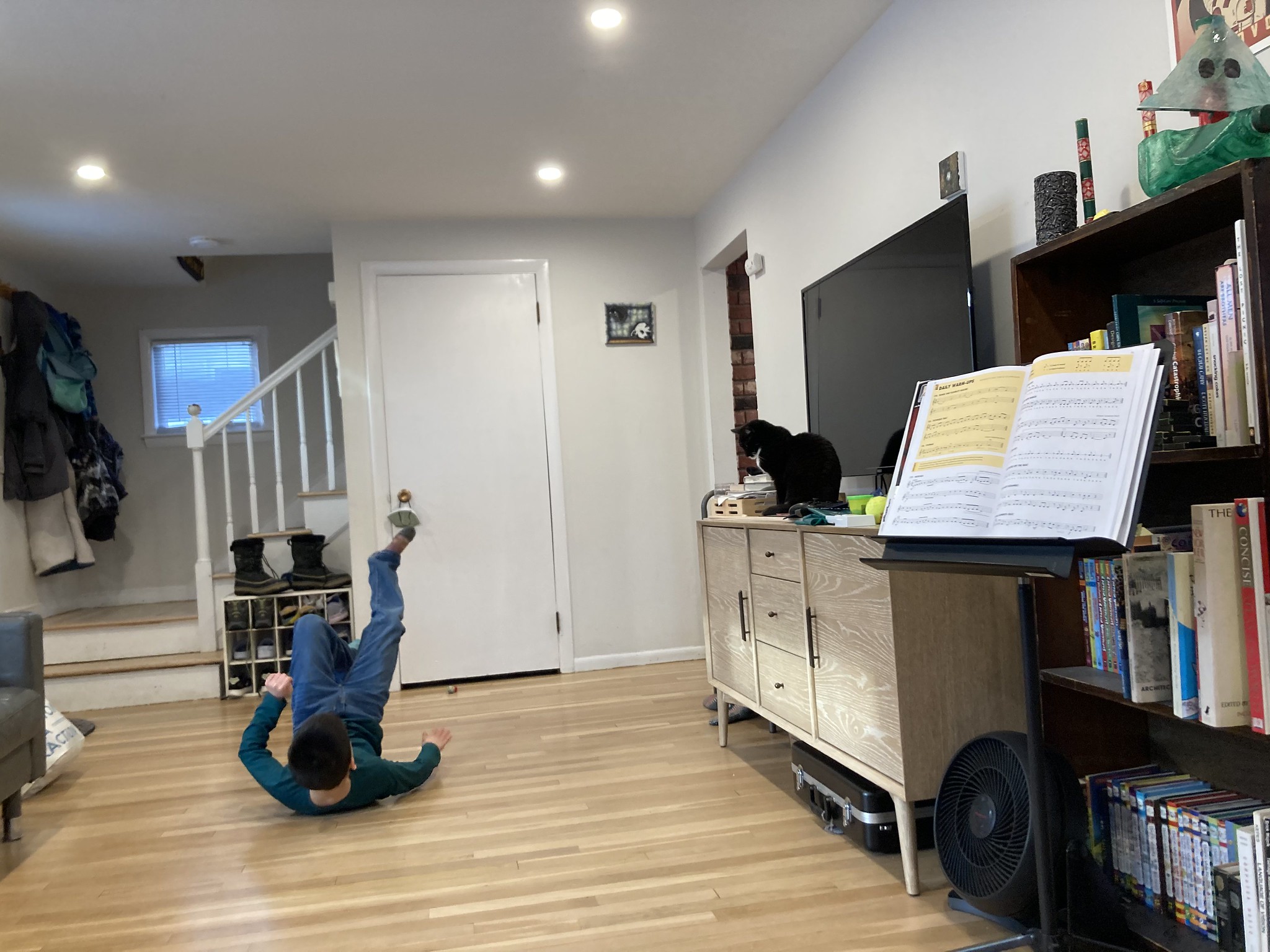 Kid slapping floor with cat on cabinet watchin' 