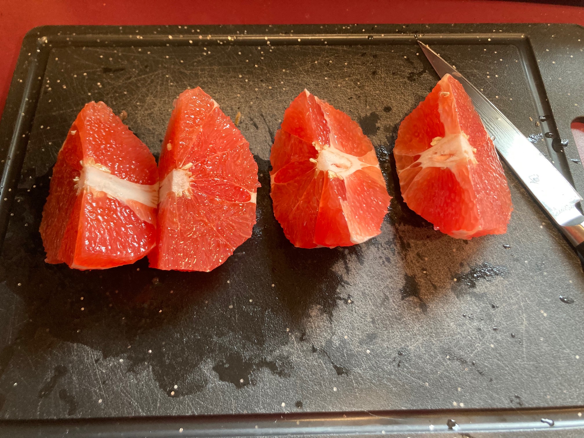 Grapefruit quarters on cutting board on red counter
