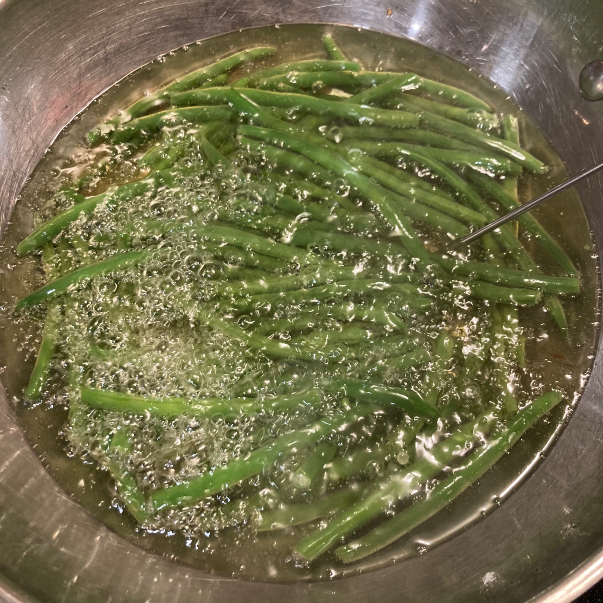 Green beans in a wok of oil