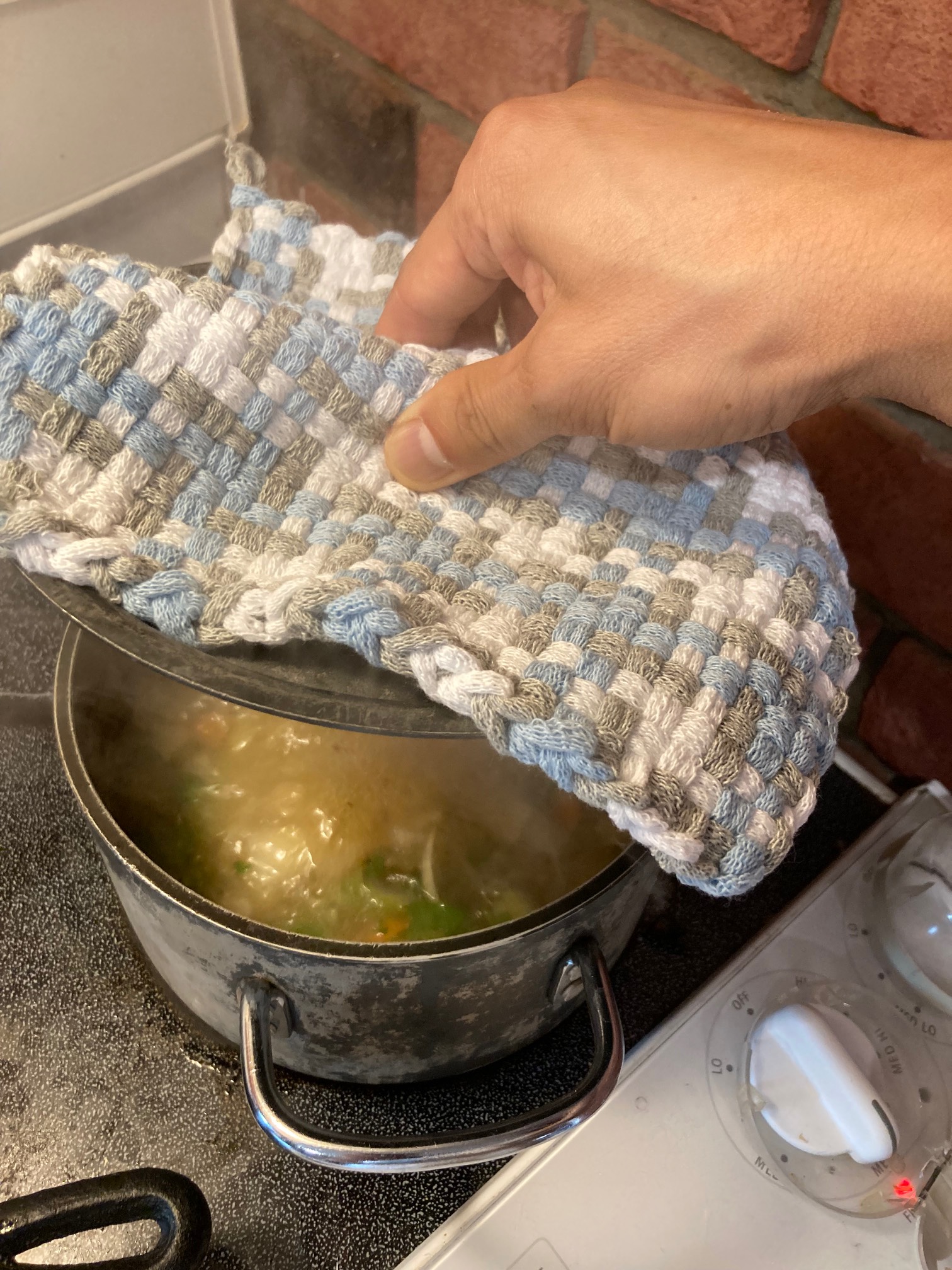 Pot holder being used to grasp pot lid