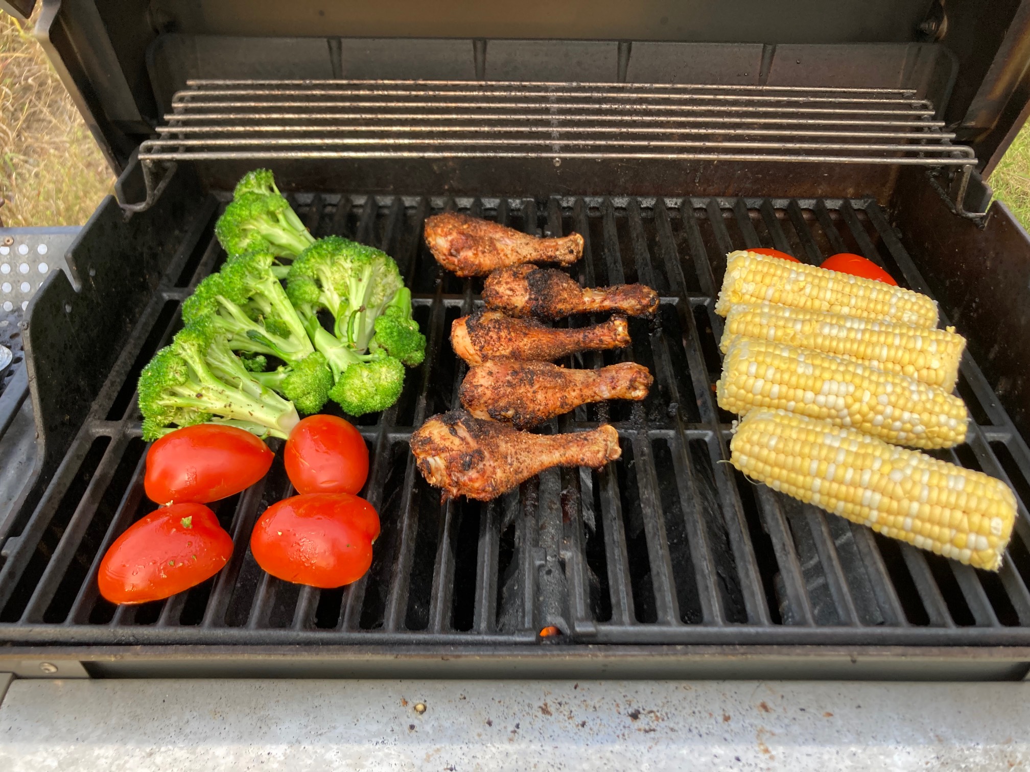 Grill with broccoli, tomato, drumsticks, corn