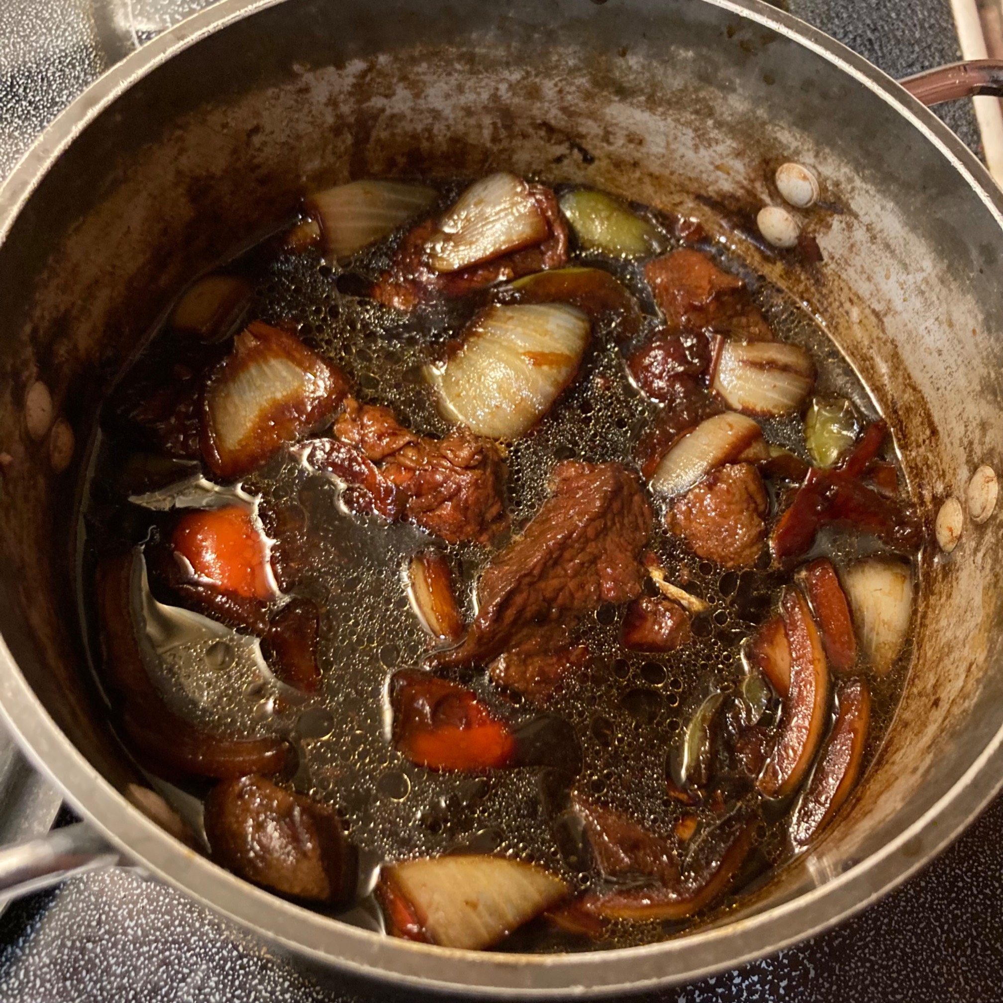A pot with peppers, onions, beef, and soy sauce.