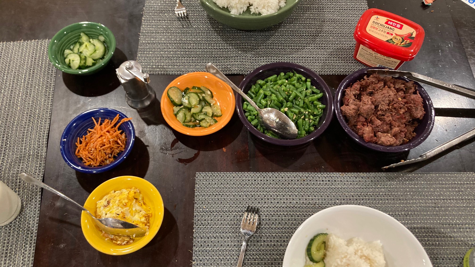 Bowls of cucumbers, carrots, eggs, beef, and rice