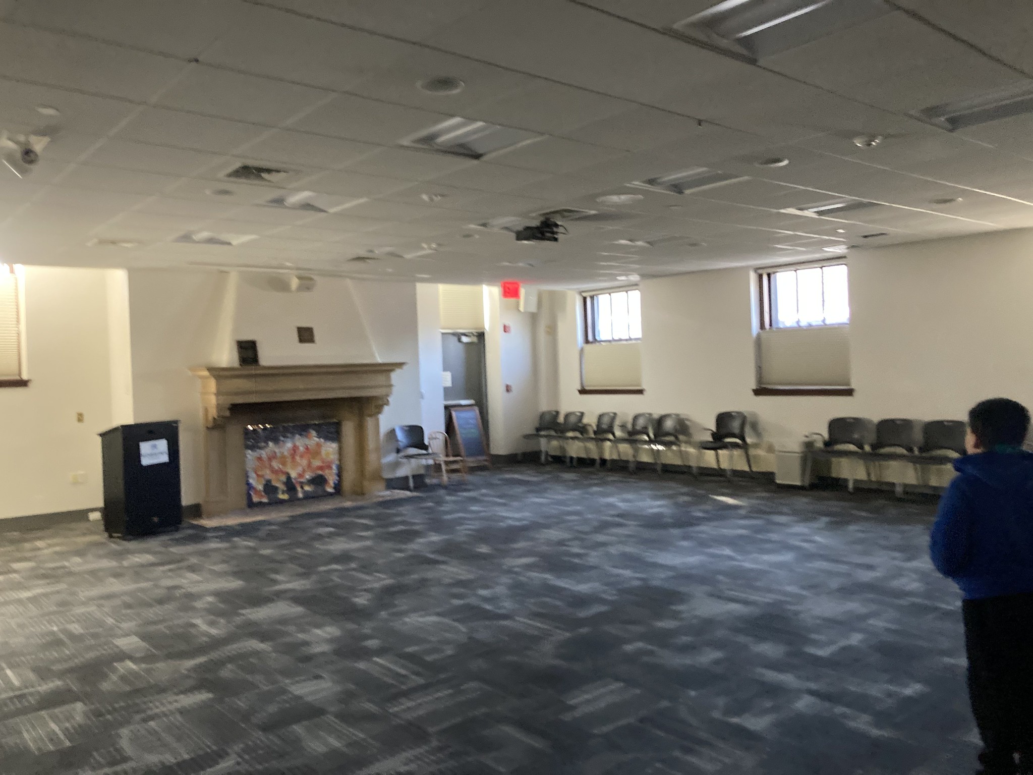 Carpeted room with chairs along walls and picture of fire in fireplace