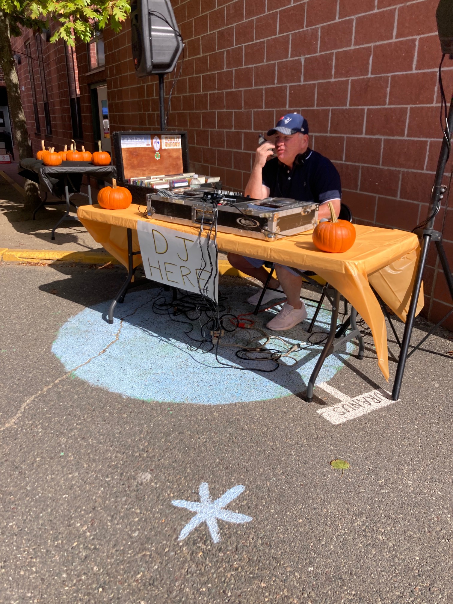Man at turntables with sign that says DJ Here