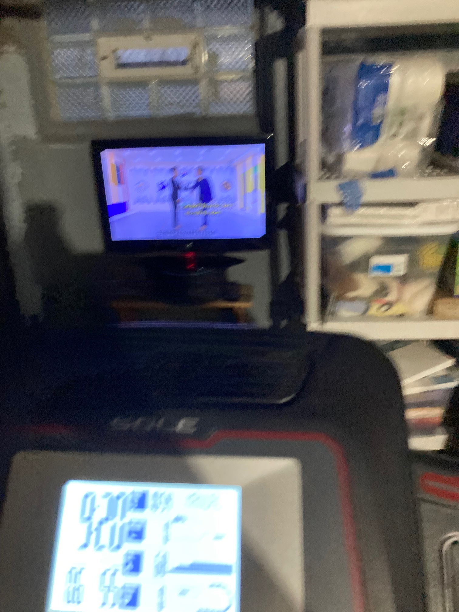 TV next to shelf behind treadmill