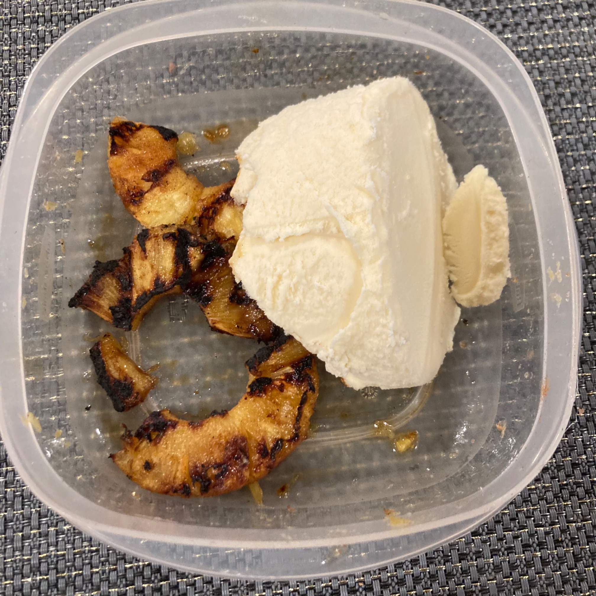 Grilled pineapple with wedge of ice cream in Tupperware 