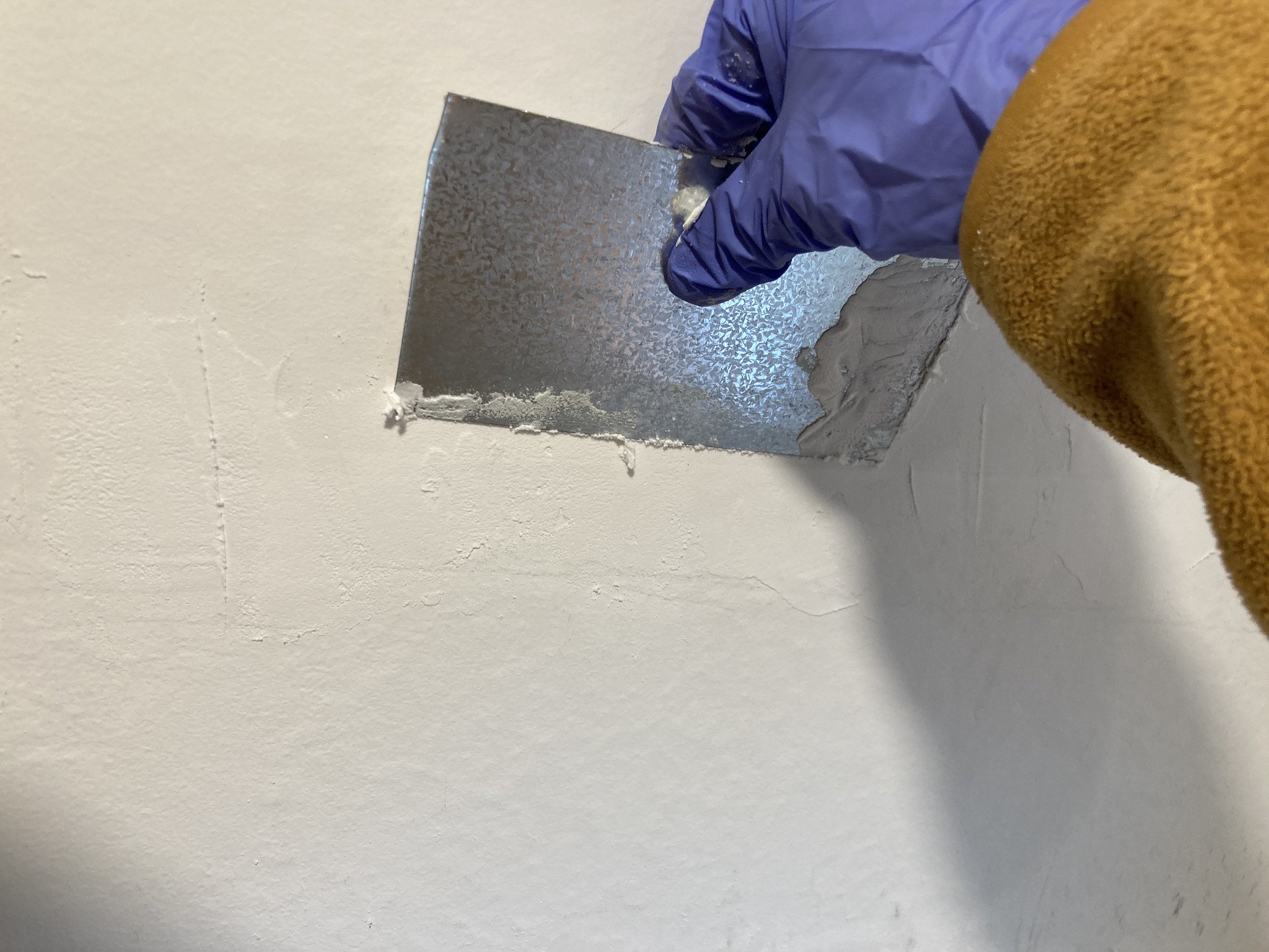 Hand holding sheet metal against wall