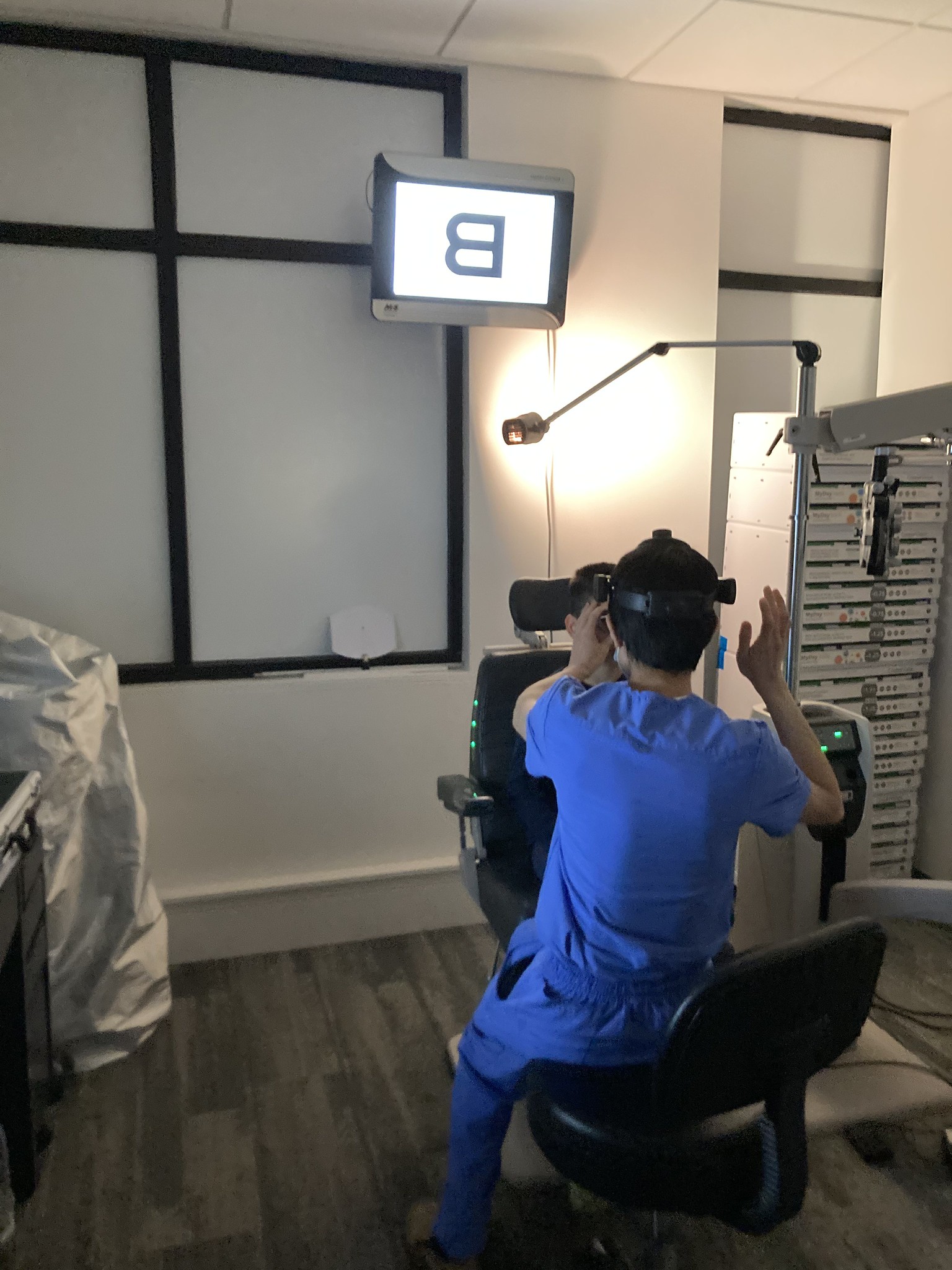 Eye chart with a big letter B and an optometrist and patient in front