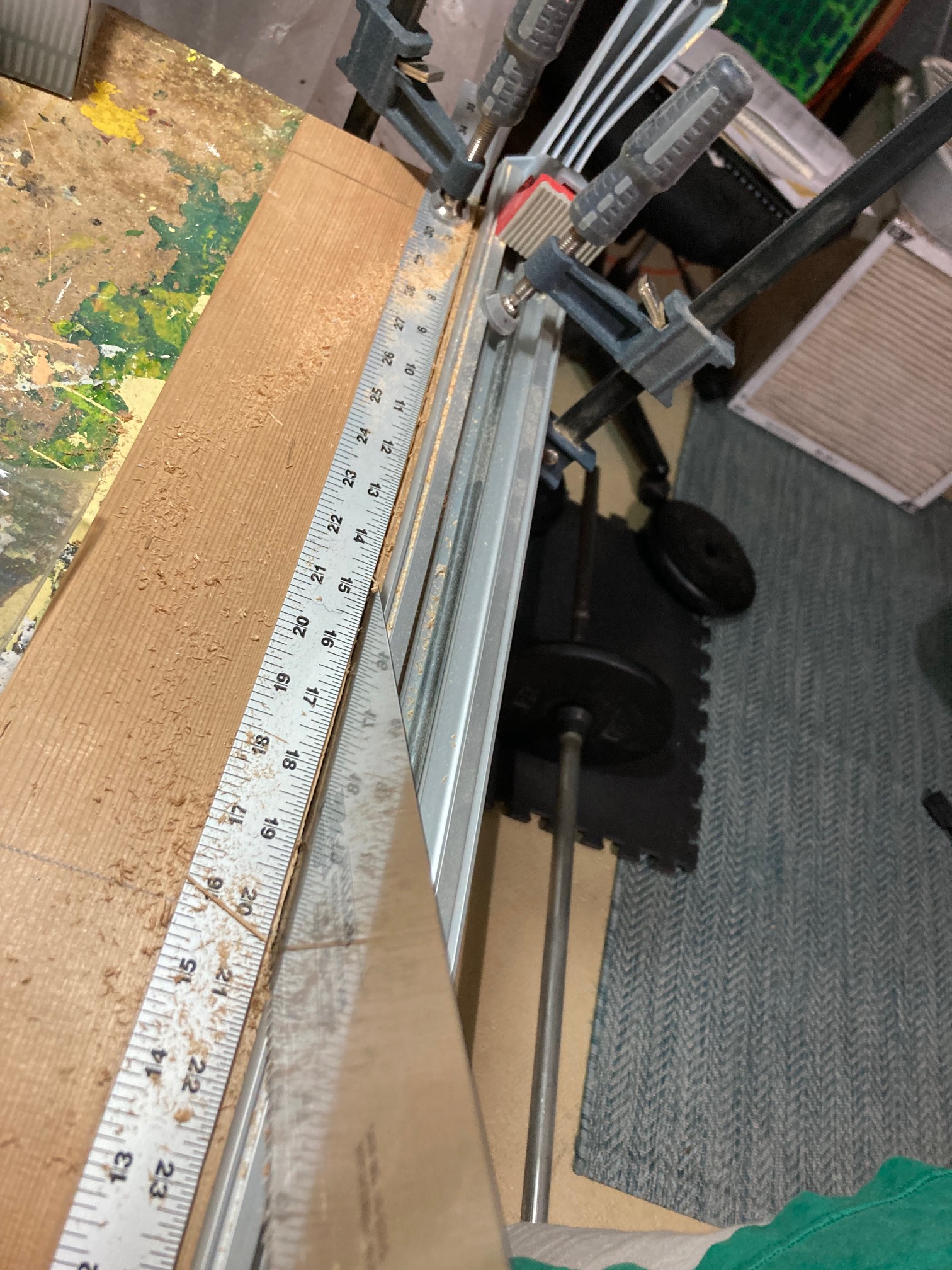 Saw cutting through board with rule clamped to it
