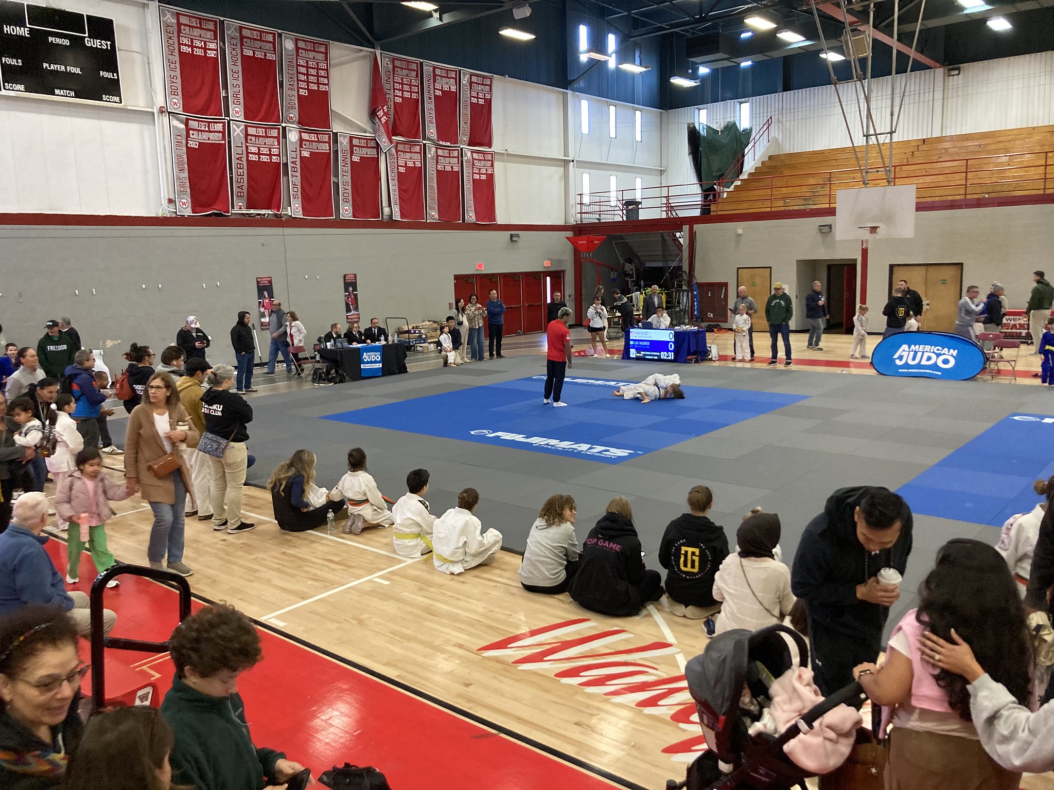 People gathered around a mat in a high school gymnasium