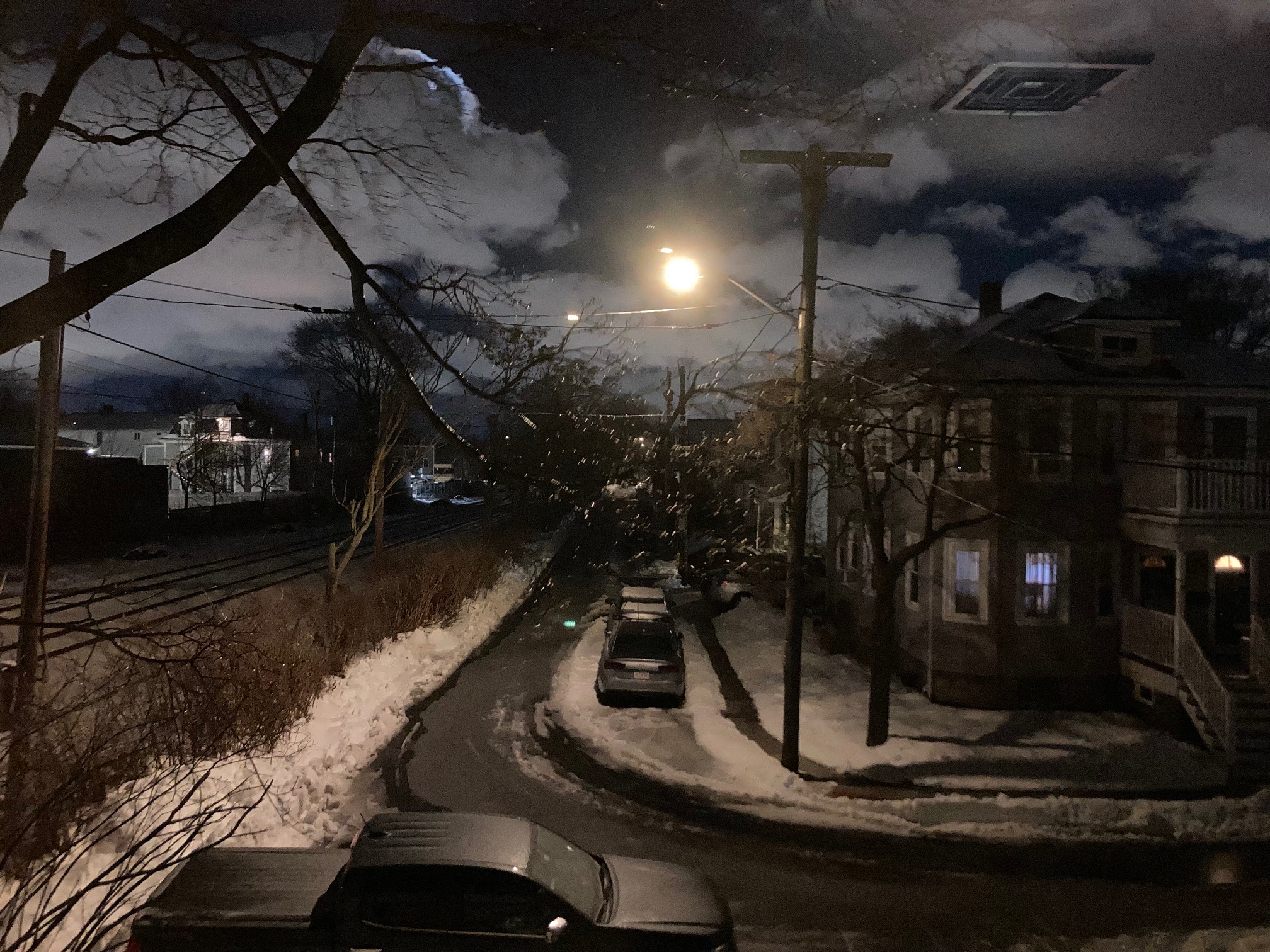 Road, cloudy sky with moon and street lights, and reflection of heat register in window