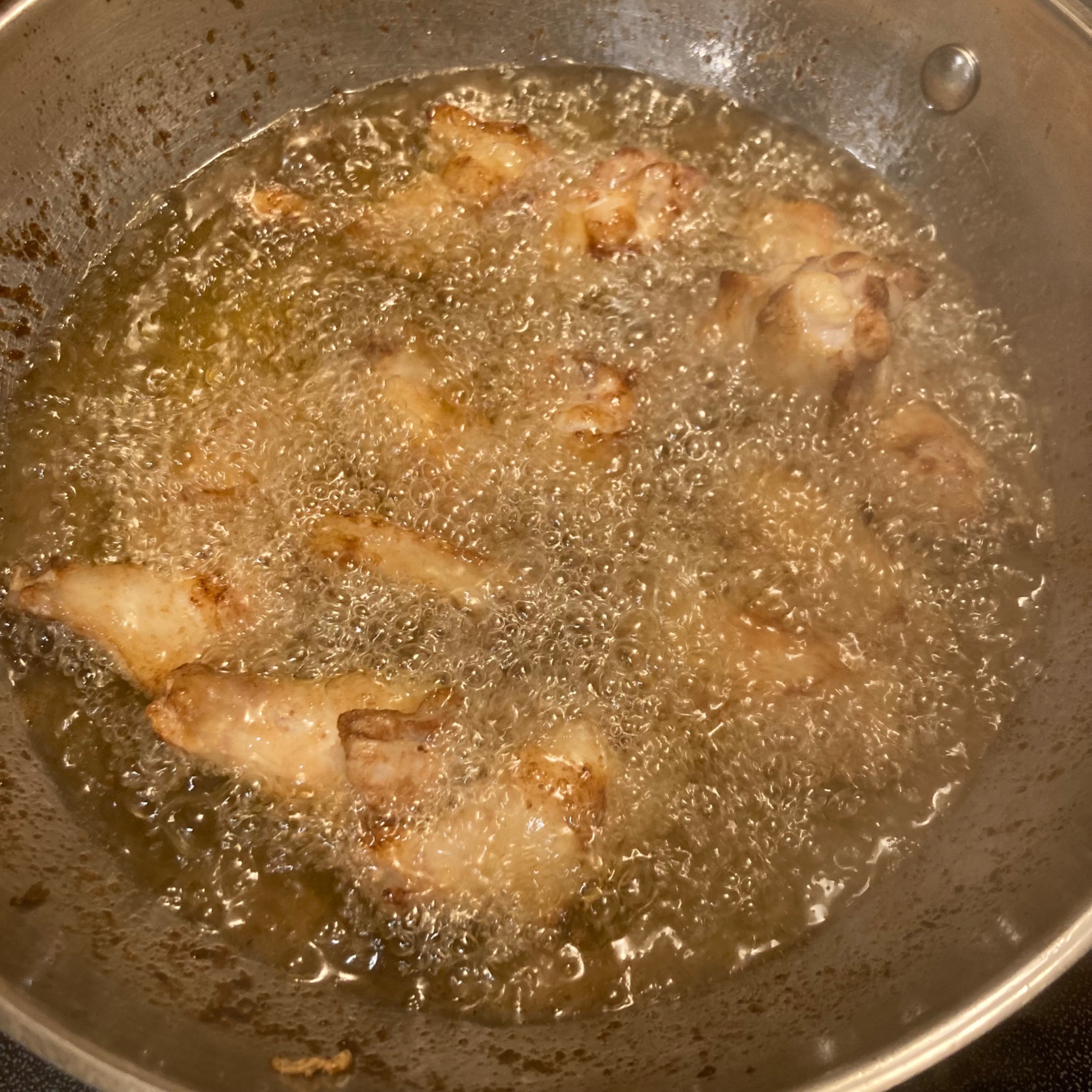 Chicken wings in a wok of oil