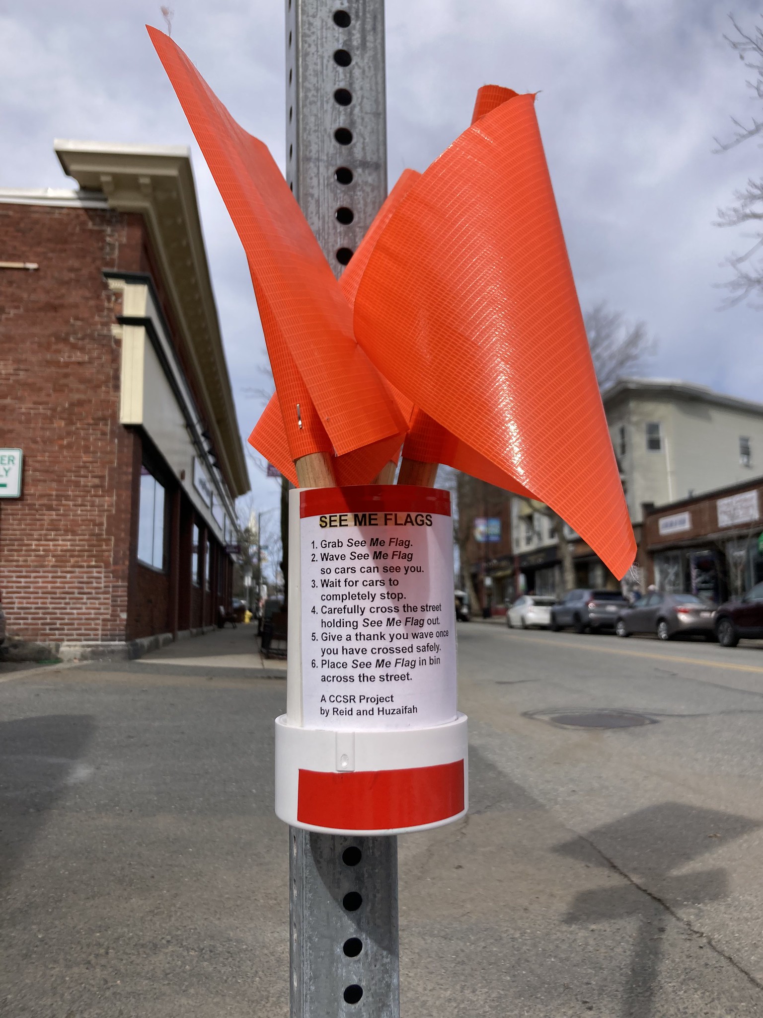 Small container of visibility flags attached to road sign