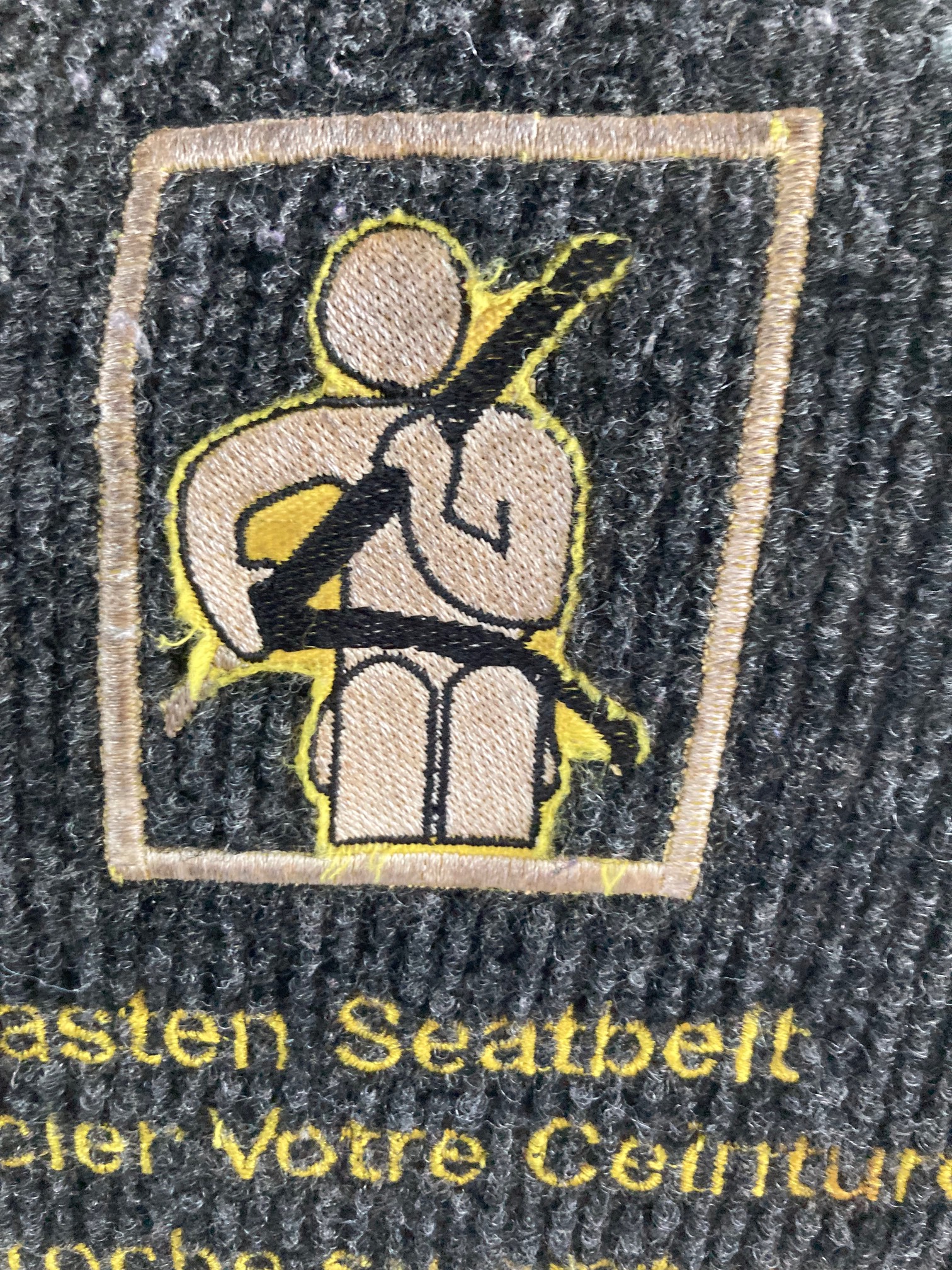 Fasten seatbelt diagram embroidered into back of bus seat