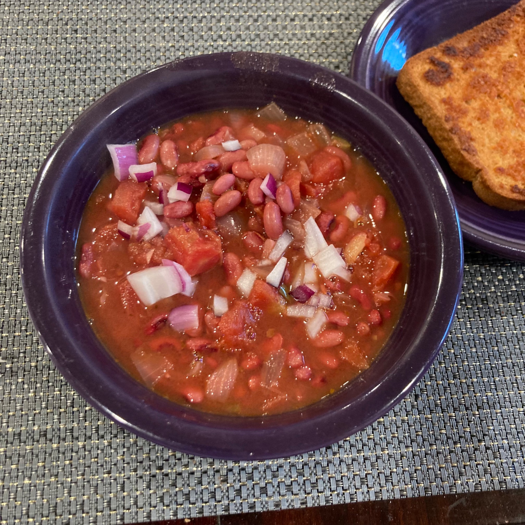 Bowl of chili and plate with garlic bread
