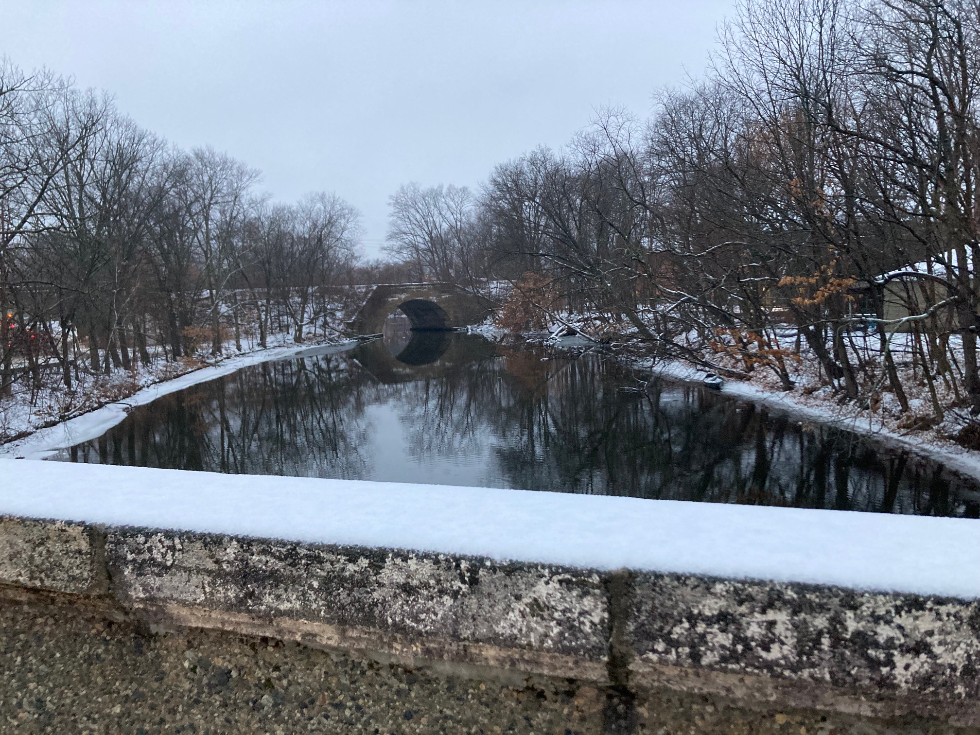 Bridge in front of a river with another snowy bridge over it in the distance