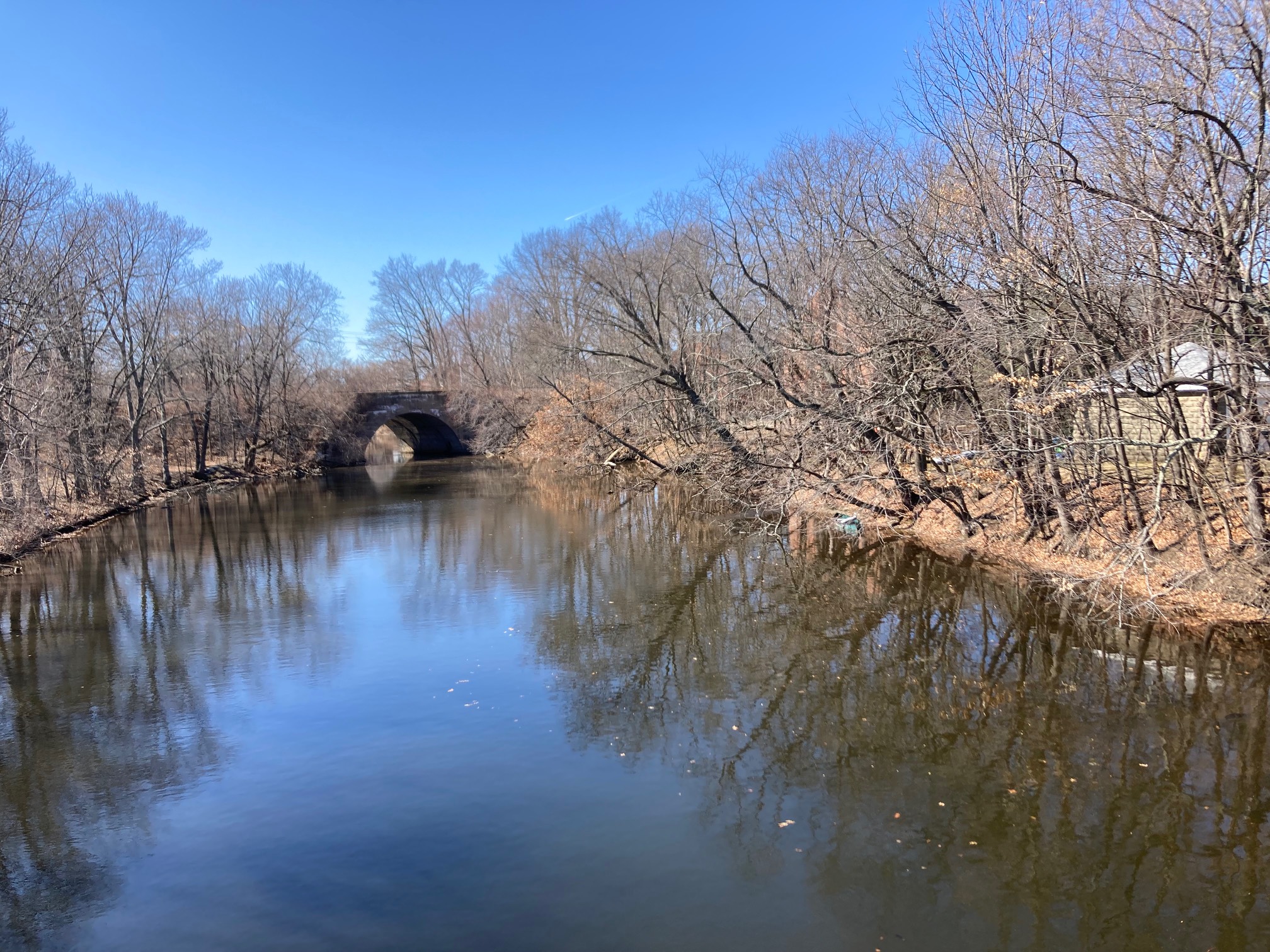 River with a bridge over it, and a small boat on the shore.