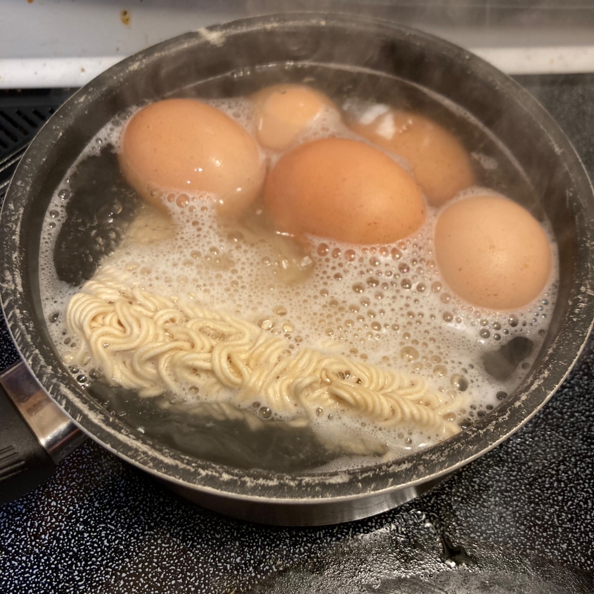 Five eggs and ramen in a small pot of boiling water